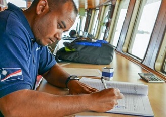Fisheries officer Beau Bigler crosschecks ship documentation as a fishing vessel seeks authorisation to use the port of Majuro. Photo: Francisco Blaha.