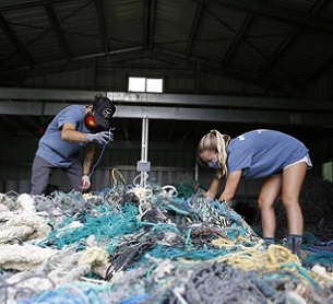 Hawaii Pacific University graduate student Drew McWhirter, left, and Raquel Corniuk, a research technician at the university's Center for Marine Debris Research, pull apart a massive entanglement of ghost nets on Wednesday, May 12, 2021 in Kaneohe, Hawaii. Credit - AP Photo/Caleb Jones.
