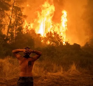 A resident watches a wildfire on Evia island, Greece, as the region endures its worst heatwave in decades, which experts have linked to the climate crisis. Photograph: Angelos Tzortzinis/AFP/Getty Images