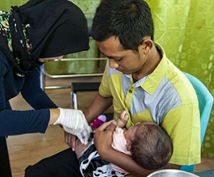 A nurse gives a baby an immunization at a healthcare clinic on the edge of the Gunung Palung National Park in West Kalimantan, Indonesia. Credit: Stephanie Gee