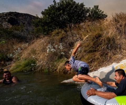 Eddie Lopez and his son, Eddie Jr. frolic near a drainage pipe along the San Gabriel River, in California, during the recent heat wave.  PHOTOGRAPH BY ROBERT GAUTHIER, LOS ANGELES TIMES/GETTY IMAGES