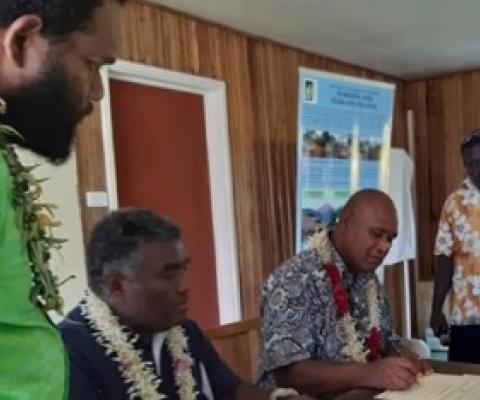 Minister Togamana signing the certificate of declaration flanked by staff of the Environmental Division MECDM and a Community elder.