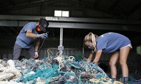 Hawaii Pacific University graduate student Drew McWhirter, left, and Raquel Corniuk, a research technician at the university's Center for Marine Debris Research, pull apart a massive entanglement of ghost nets on Wednesday, May 12, 2021 in Kaneohe, Hawaii. Credit - AP Photo/Caleb Jones.